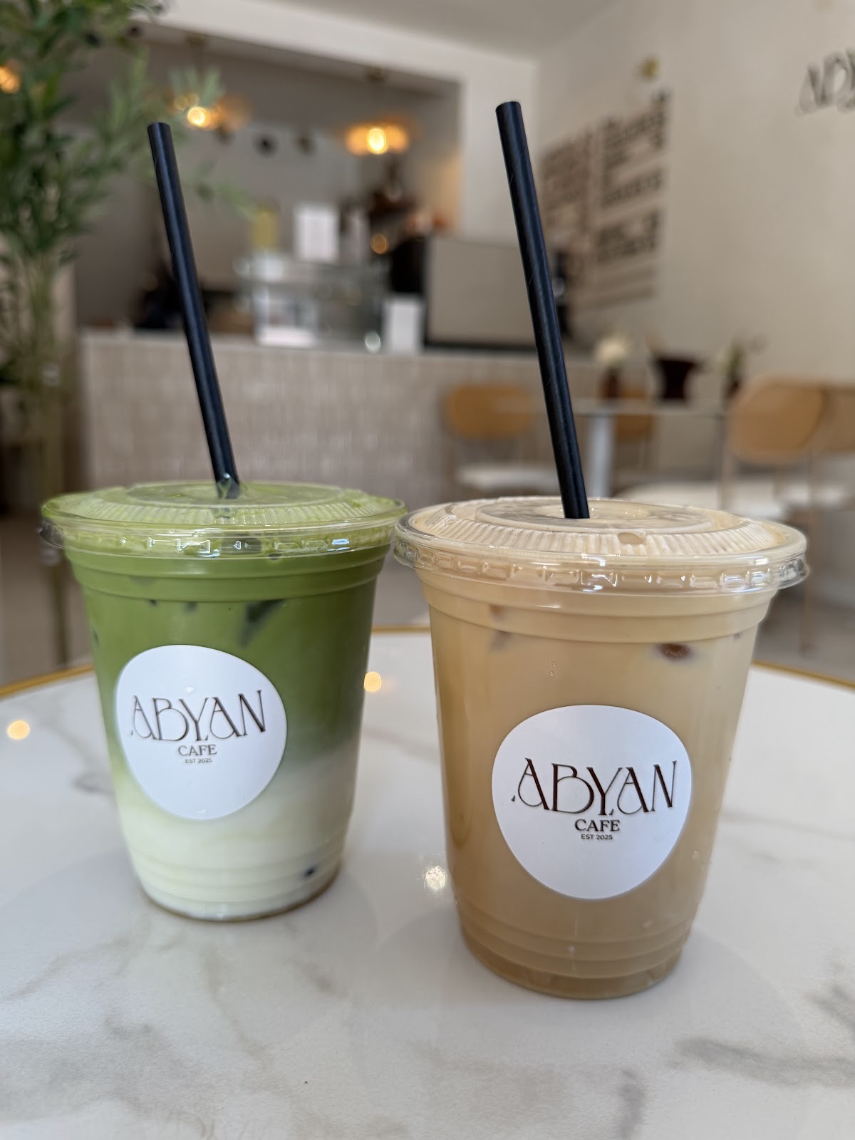 An iced coffee and a matcha latte side by side on marble